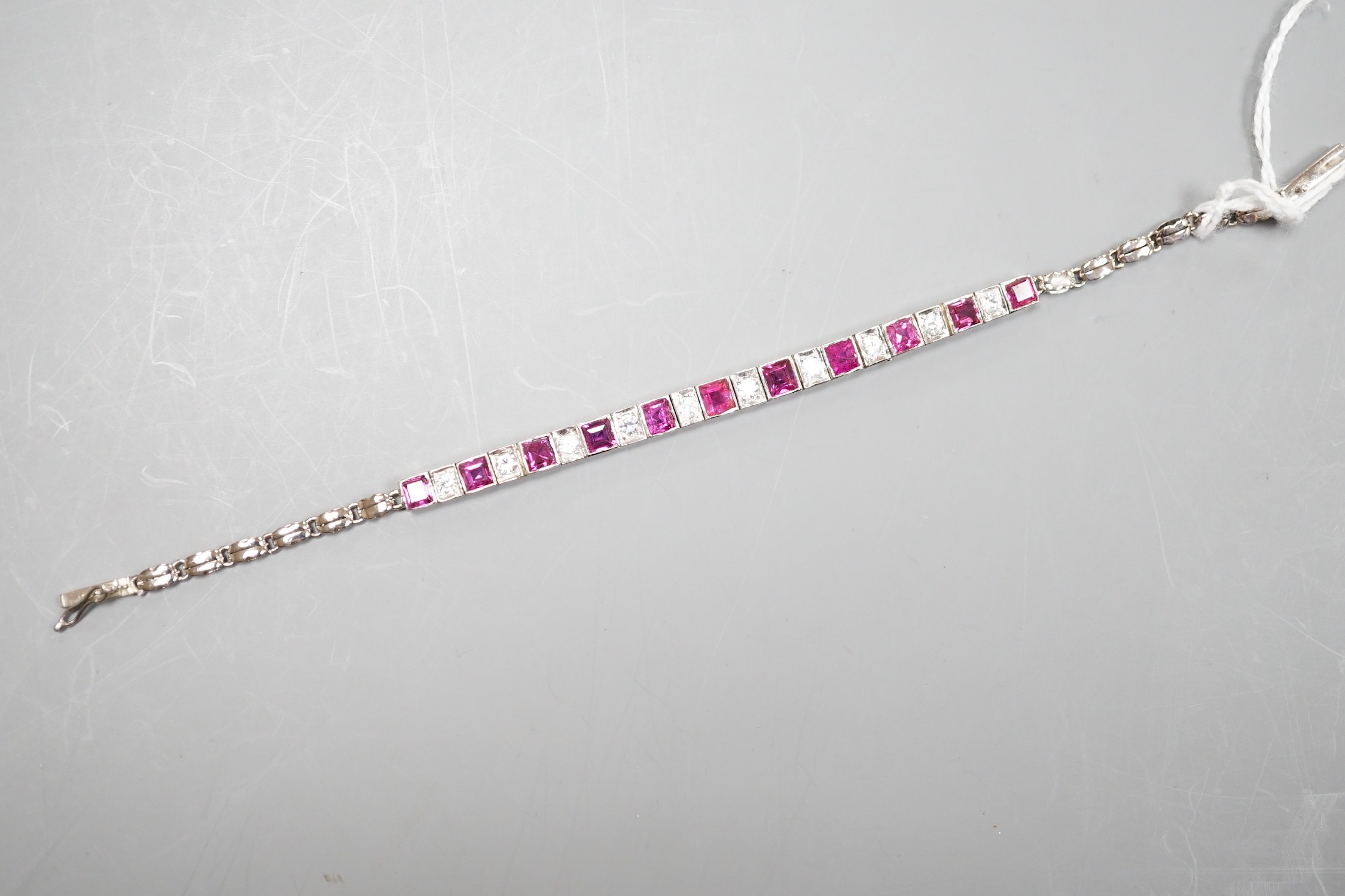 A white metal, ruby and white spinel set line bracelet, 16cm, gross weight 8.4 grams.